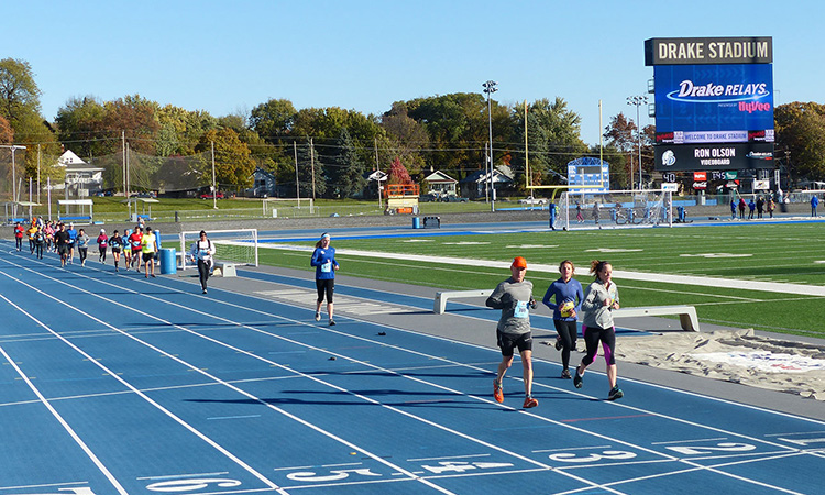 Runners circle the Drake University track at the Des Moines Marathon
