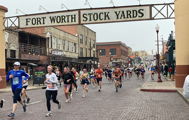 Runners below the Historic Fort Worth Stockyards sign at The Cowtown